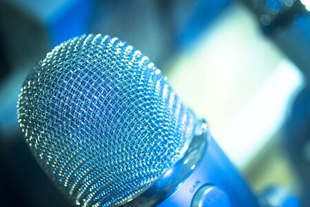 Professional studio voice recording concert singing microphone showing metallic body. Artistic color digital photo with shallow depth of focus and negative space and blurred background.の写真素材