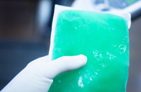 Green physiotherapy cold muscle injury gel pack forzen in freezer in sports injury medical clinic for physical therapy and rehabilitation for orthopedics and traumatology in hand of physiotherapist.の写真素材