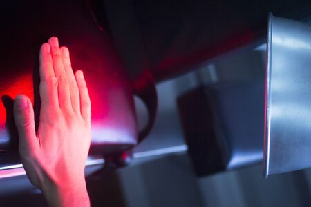 Patient hand in red physiotherapy heat treatment under hot light.の写真素材