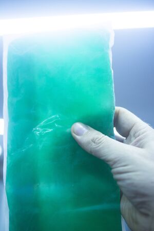 Green physiotherapy cold muscle injury gel pack forzen in freezer in sports injury medical clinic for physical therapy and rehabilitation for orthopedics and traumatology in hand of physiotherapist.の写真素材