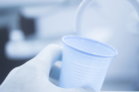 Dentist's water rinse cup tap pip filler in dental clinic in artistic blue purple white tones.の写真素材