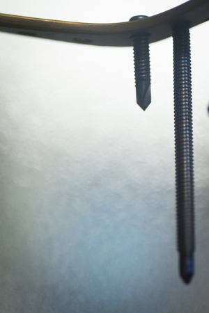 Traumatology and orthopedic surgery implant titanium plate and screws in semi silhouette against plain studio background.の写真素材