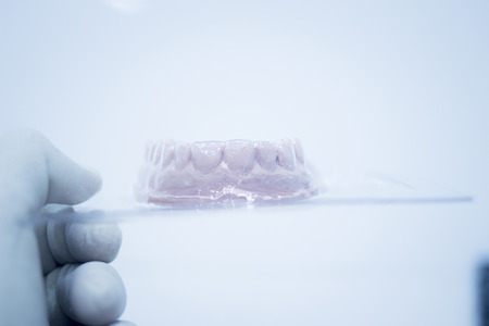 Dental mold dentist clay teeth plate ceramic colored cast model in steril plastic vacuum wrap showing tooth decay of patient in dental clinic office surgery used for diagnosis and treatment.の写真素材