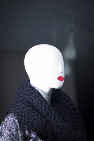 Shop dummy fashion mannequin in department store boutique window wearing current trends in garments.