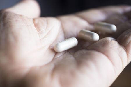 Multivitamin mineral pills health food supplements in hand of man.の写真素材