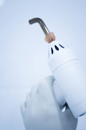 Dental filling gun in dentist hand in clinic office surgery used to harden dental fillings to treat...