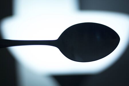 Spoon silhouette at night symbolic artistic photograph.の写真素材
