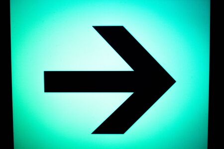 Airport information sign light panel giving directions with arrow in departure lounge for air travelllers.の写真素材