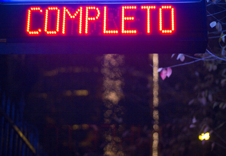 Car park light sign at night photo in Spain showing completo in Spanish or full.の写真素材