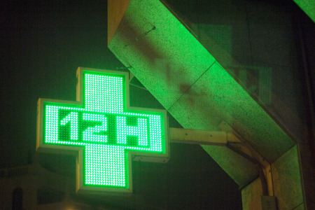 Pharmacy neon light chemists 12 hour open cross sign at night photo.の写真素材