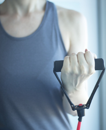 Woman with slim, fit and attractive body in 40's exercising with resistance exercise bands in gym bicep exercise.の写真素材