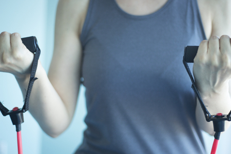 Woman with slim, fit and attractive body in 40's exercising with resistance exercise bands in gym bicep exercise.の写真素材