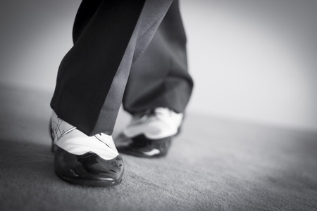 Male latin and salsa dancer in black and white jazz dancing shoes in light and dark on stage monochrome photo.の写真素材