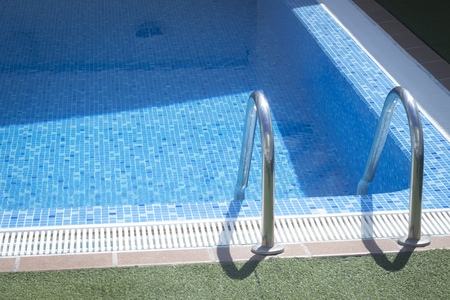 Outdoor swimming pool water on hot summer's day in luxury hotel resort.
