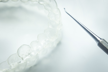 Invisible teeth aligner cosmetic orthodontic brackets used to straighten and align teeth in patient with clear plastic see through aesthetic look.の写真素材