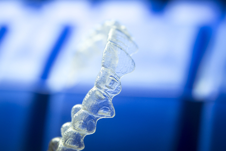 Invisible teeth aligner cosmetic orthodontic brackets used to straighten and align teeth in patient with clear plastic see through aesthetic look.の写真素材