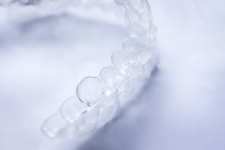 Invisible teeth aligner cosmetic orthodontic brackets used to straighten and align teeth in patient with clear plastic see through aesthetic look.の写真素材