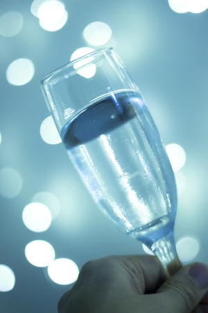 Champagne sparkling wine glass in disco party at night with defocused festive Christmas and New Year lights in nightclub.の写真素材