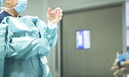 Surgeon in hospital surgery dressing in sterile uniform "scrubs" in operating theater emergency room in surgical operation.の写真素材