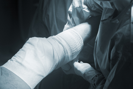 Nurse bandaging after knee surgery hospital operation medical procedure in emergency room operating theater.の写真素材