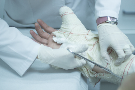 Doctor removing a plaster cast and bandages to patient forearm and wrist to immobilize after fracture injury.の写真素材