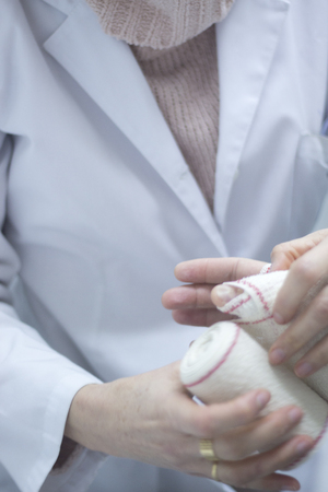 Doctor applying a plaster cast and bandages to patient forearm and wrist to immobilize after fracture injury.の写真素材