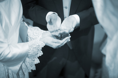 Wedding bride in bridal gown dress and groom in suit echanging coins in catholic christian marriage ceremony.の写真素材
