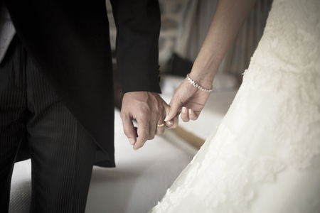Wedding bride in bridal gown dress and groom in suit holding hands in marriage ceremony.の写真素材