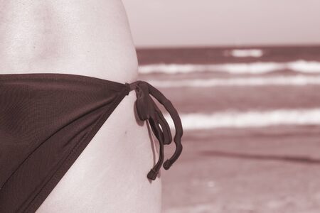 Slim, attractive, sporty sexy young lady in bikini swimwear on beach by the ocean in summer.の写真素材