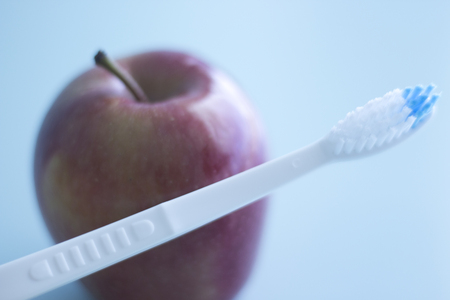 Dental toothbrush to clean teeth and fresh red apple for healthy eating.の写真素材