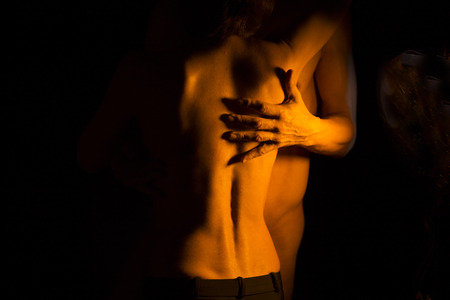 Sexy couple nude slim athletic man and erotic slender lady naked touching bodies in the dark.の写真素材