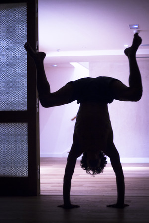 Male yoga teacher doing handstand inversion alisthenics and yoga asana practice in gym fitness pilates studio.の写真素材