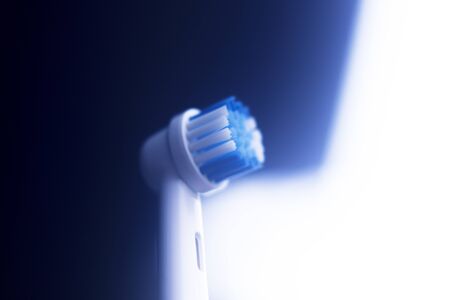 Electric modern tooth brush closeup on plain abstract background.