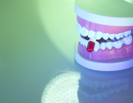 Dental teeth, mouth, gums dentists teaching model showing each tooth and medication drug pill.