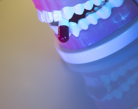 Dental teeth, mouth, gums dentists teaching model showing each tooth and medication drug pill.