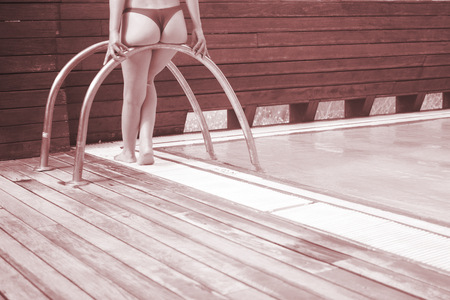 Sexy slim young lady by swimming pool in gstring bikini swimwear.の写真素材