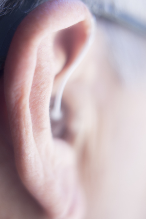 Modern digital in the ear hearing aid for deafness and the hard of hearing in aged man's ear.の写真素材