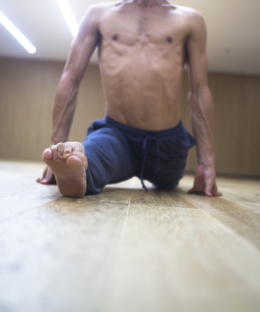 Man yoga teacher practising in gym fitness studio doing advanced asana posture.の写真素材