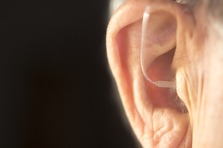 Digital modern hearing aid in the ear of aged old man.の写真素材