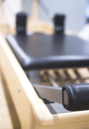 Reformer pilates studio machine for fitness workouts in gym.