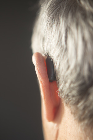 Digital modern hearing aid in the ear of aged old man.の写真素材