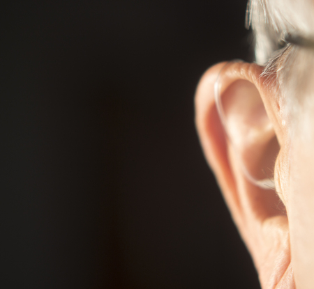 Digital modern hearing aid in the ear of aged old man.の写真素材