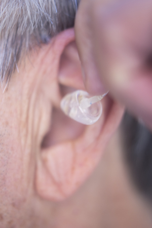 Modern digital in the ear hearing aid for deafness and the hard of hearing in aged man's ear.
