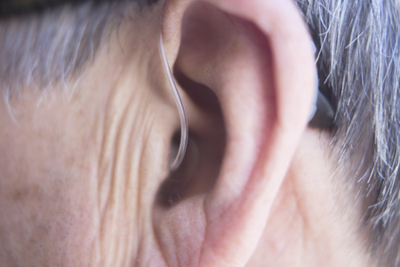 Modern digital in the ear hearing aid for deafness and the hard of hearing in aged man's ear.の写真素材