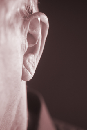 Digital modern hearing aid in the ear of aged old man.の写真素材
