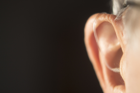 Digital modern hearing aid in the ear of aged old man.の写真素材