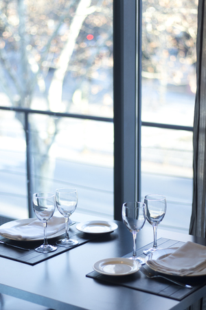 Restaurant cafe bar in luxury hotel with place settings for breakfast, lunch and dinner with wine water glasses and plates.の写真素材
