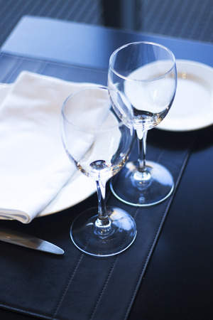 Restaurant cafe bar in luxury hotel with place settings for breakfast, lunch and dinner with wine water glasses and plates.の写真素材