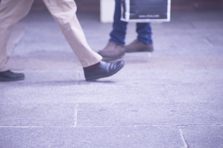 People walking in busy urban city shopping street sidewalk pavement shoes feet and legs.の写真素材