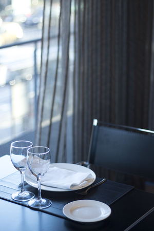 Restaurant cafe bar in luxury hotel with place settings for breakfast, lunch and dinner with wine water glasses and plates.の写真素材
